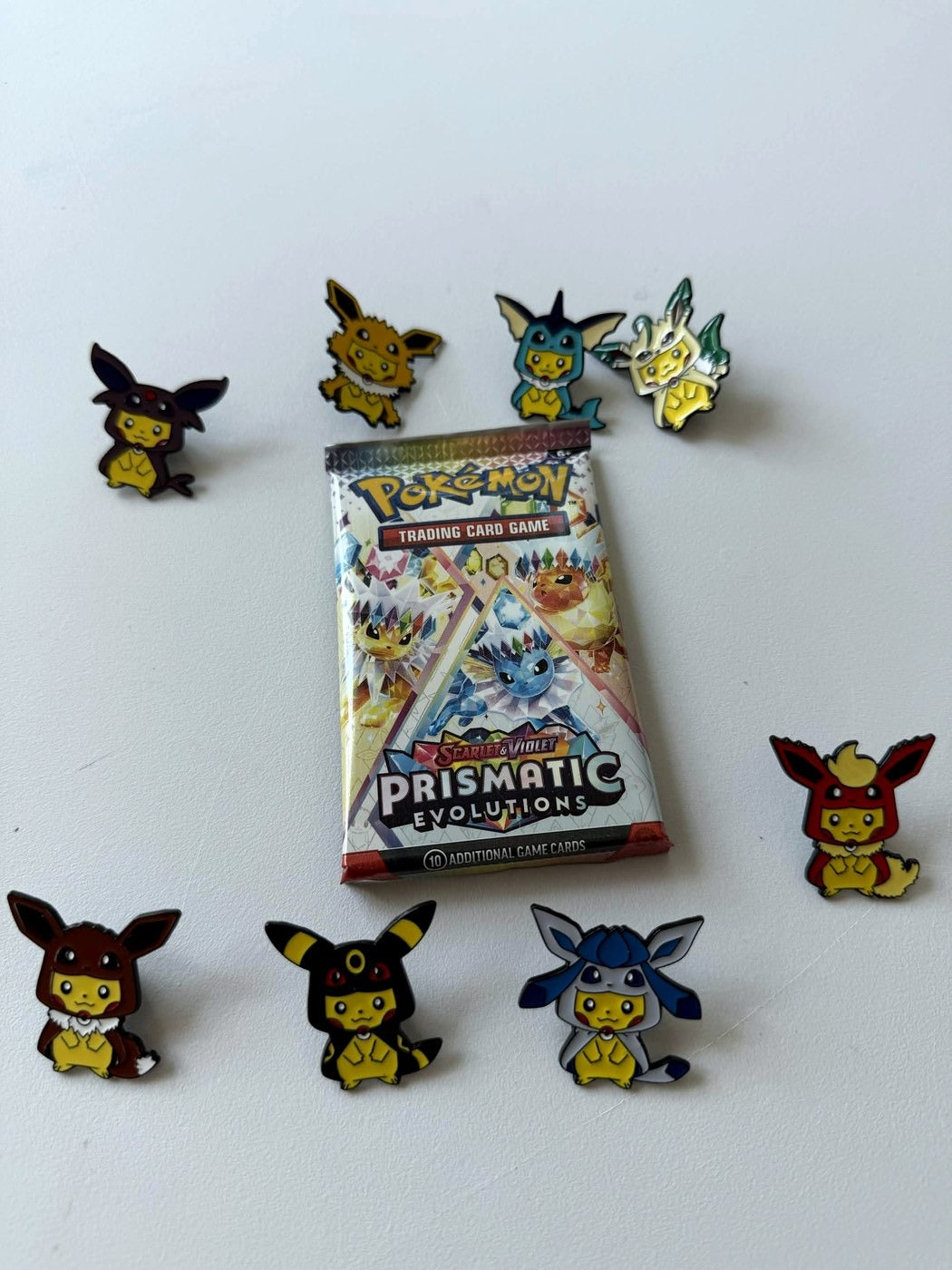 Pokémon trading card game pack with character pins on a white background