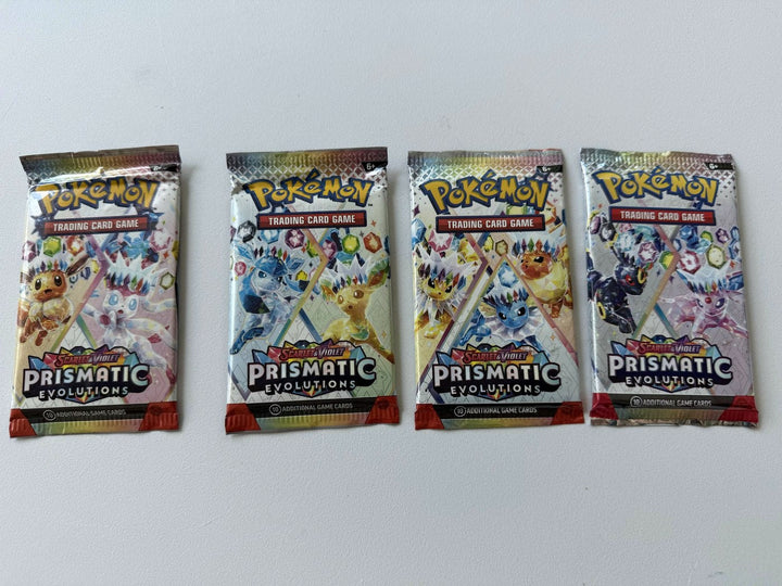 Four packs of Prismatic Evolution Pokemon trading cards on a white background