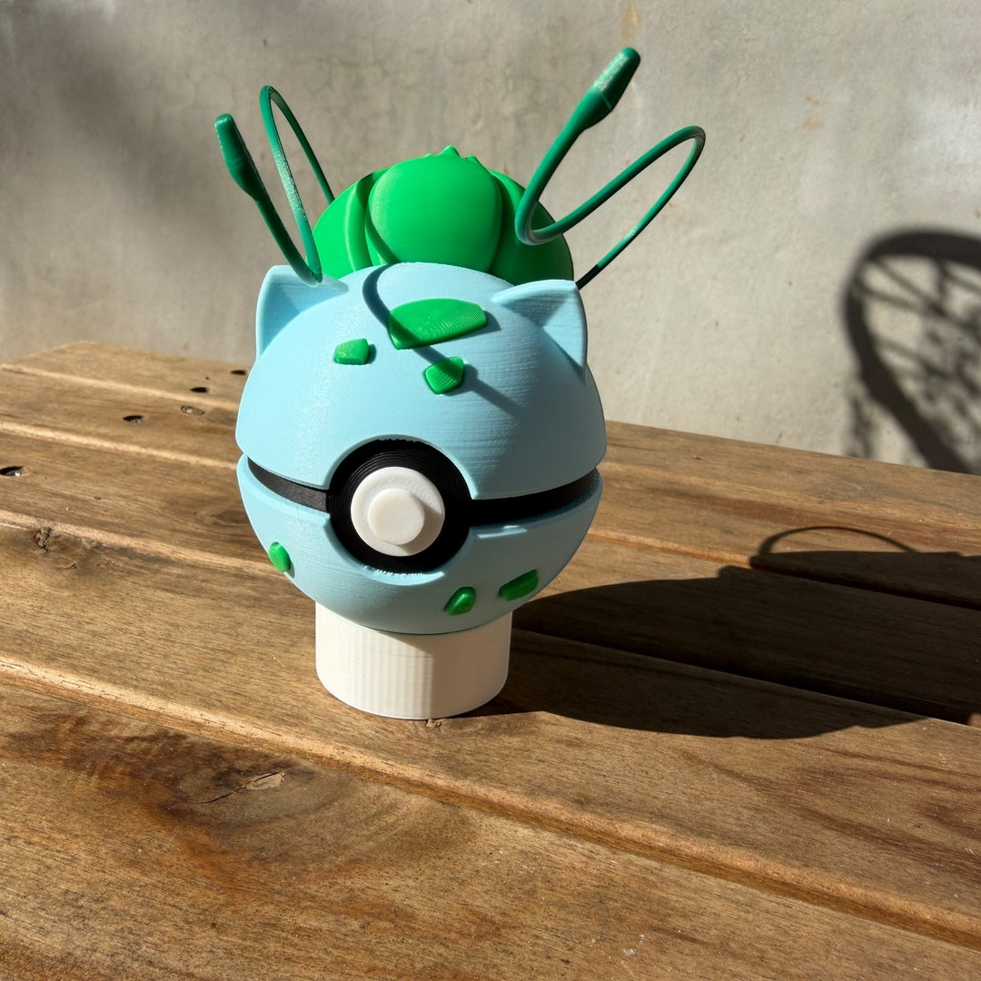 Green and blue creature head on a wooden surface with a concrete wall background